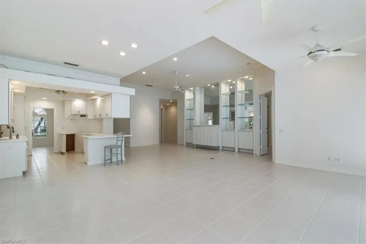 Unfurnished living room with sink, light tile patterned flooring, and ceiling fan