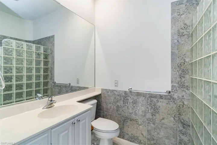 Bathroom featuring vanity, tile walls, and toilet