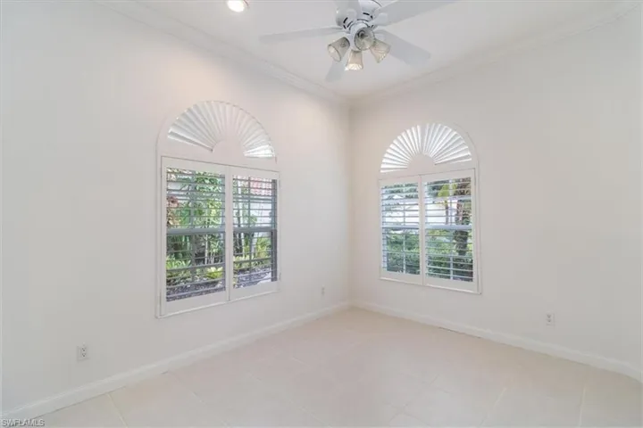 Tiled empty room with ceiling fan and crown molding