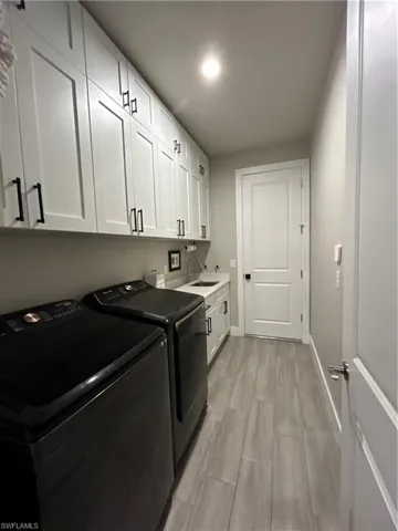 Washroom with light wood-style flooring, washer and dryer, cabinet space, and recessed lighting