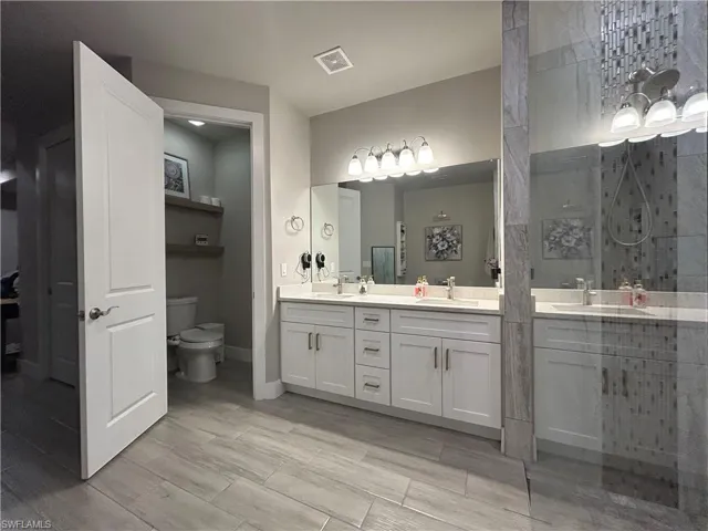 Bathroom with double vanity, a stall shower, and wood look finish floors