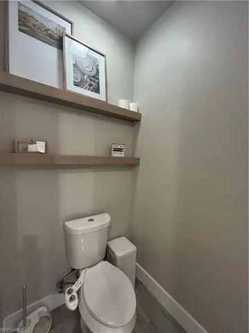 Private toilet room featuring baseboards and wood finished looking floors