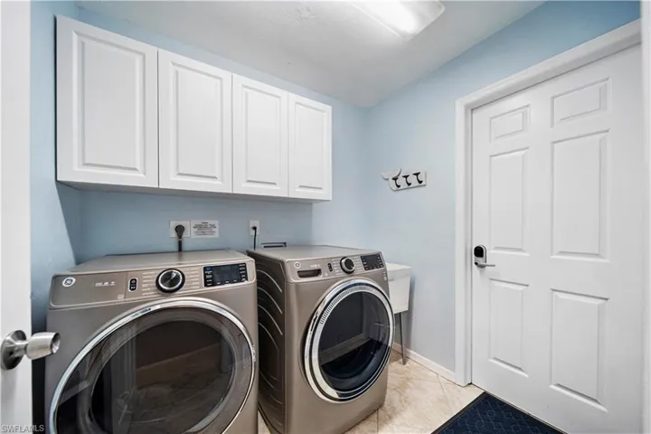 Laundry room with cabinets, light tile patterned flooring, and washer and dryer