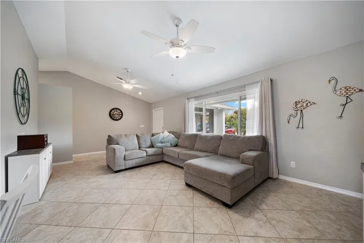 Tiled living room featuring lofted ceiling and ceiling fan