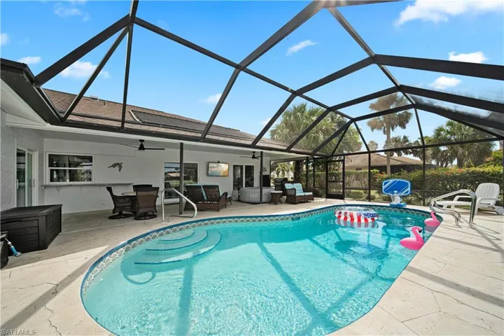 View of pool with ceiling fan, glass enclosure, and a patio area