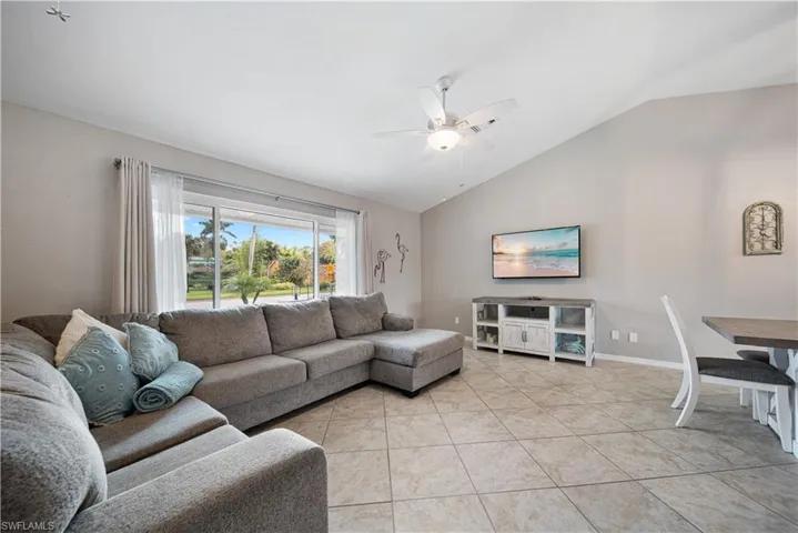 Living room with light tile patterned flooring, vaulted ceiling, and ceiling fan