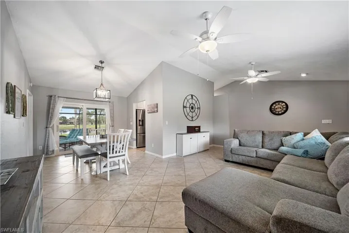 Living room featuring light tile patterned flooring, ceiling fan, and lofted ceiling