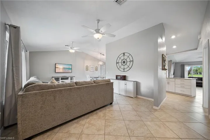 Living room featuring lofted ceiling, light tile patterned floors, and ceiling fan