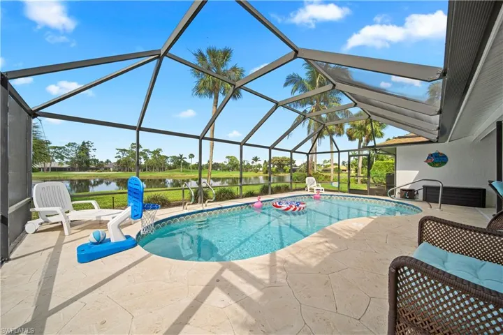 View of pool featuring a water view, a patio, and glass enclosure