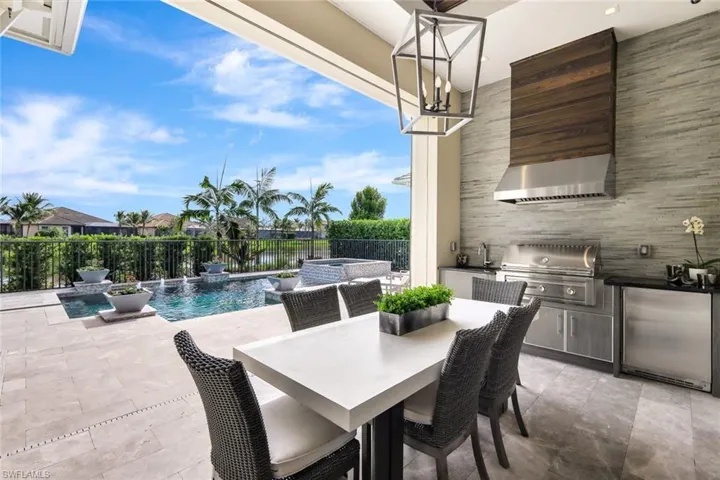 View of patio with an outdoor kitchen, a pool with hot tub, pool water feature, sink, and a grill