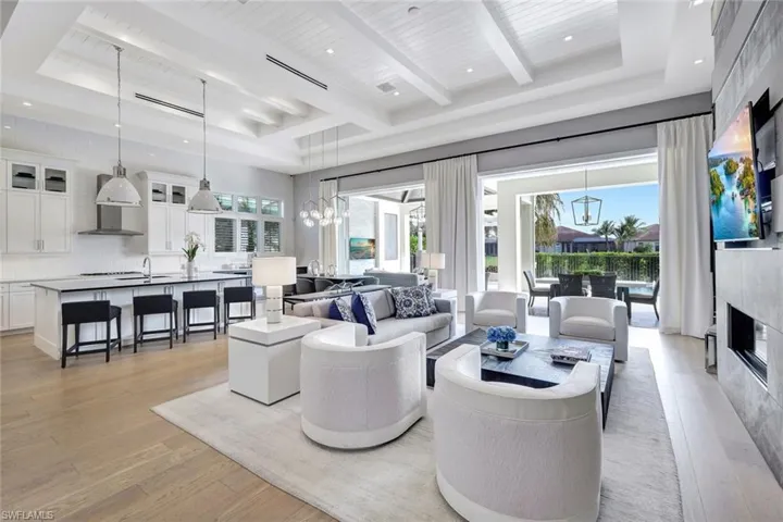 Living room featuring a tray ceiling, a premium fireplace, beamed ceiling, and light wood-type flooring
