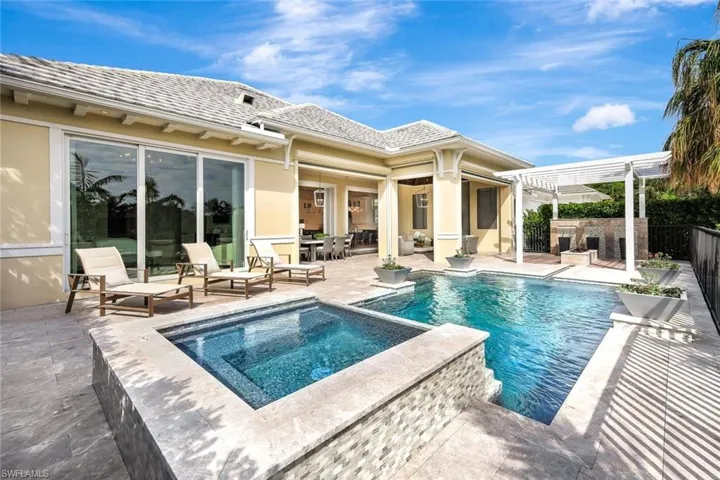View of swimming pool with an outdoor stone fireplace, an in ground hot tub, a pergola, and a patio