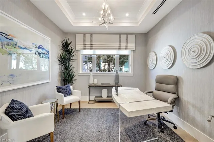 Office featuring hardwood / wood-style floors, a raised ceiling, and a chandelier