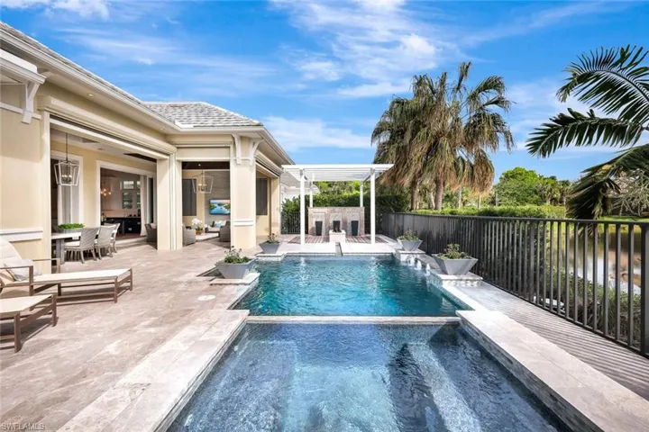 View of swimming pool with pool water feature, an outdoor bar, and a patio area