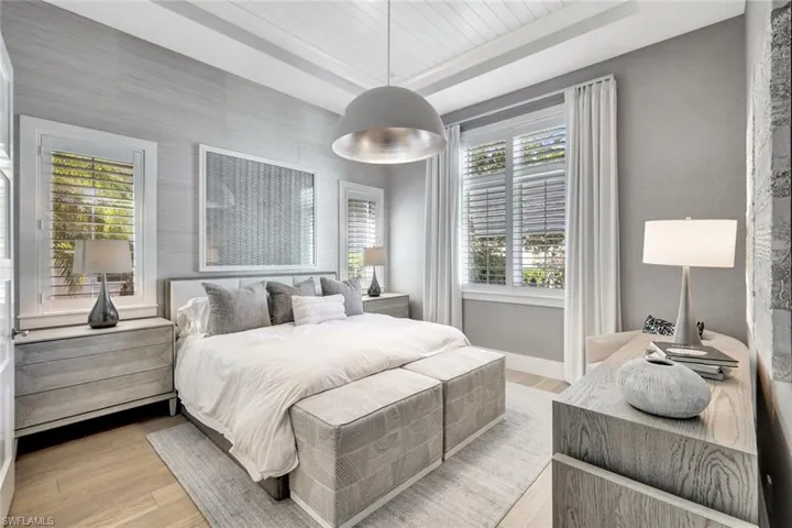 Bedroom featuring a raised ceiling, multiple windows, wood ceiling, and light hardwood / wood-style floors