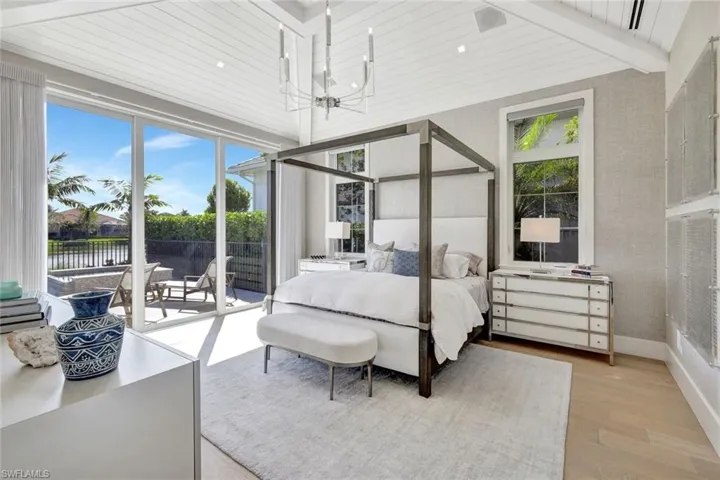 Bedroom with beam ceiling, an inviting chandelier, light hardwood / wood-style flooring, access to outside, and a water view