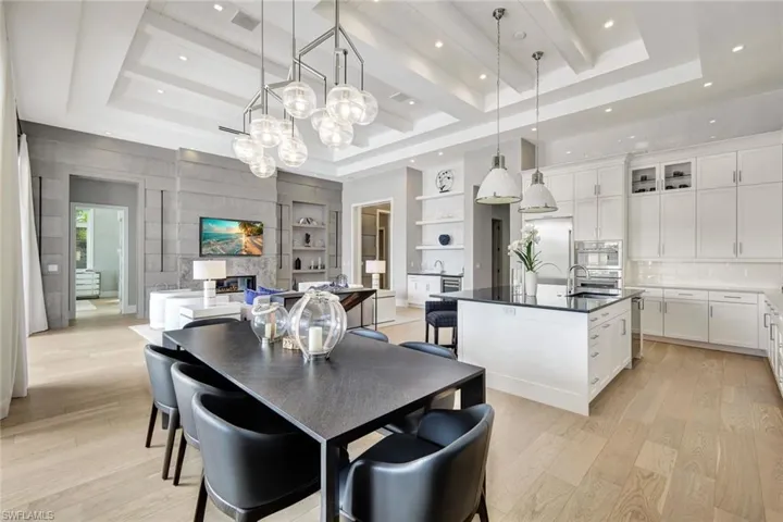 Dining room with built in shelves, light wood-type flooring, a raised ceiling, and sink