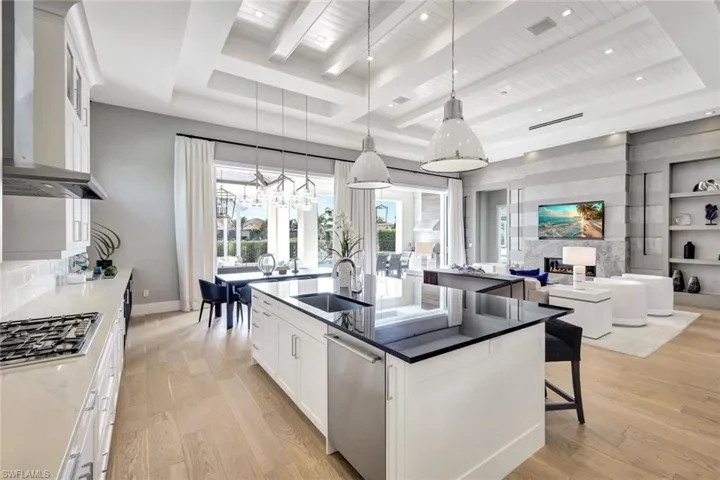 Kitchen featuring white cabinetry, sink, hanging light fixtures, appliances with stainless steel finishes, and light wood-type flooring