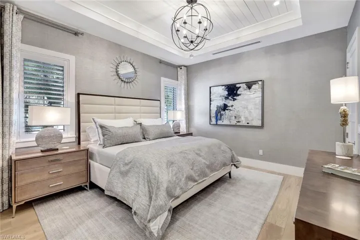 Bedroom featuring wooden ceiling, a raised ceiling, light wood-type flooring, and an inviting chandelier
