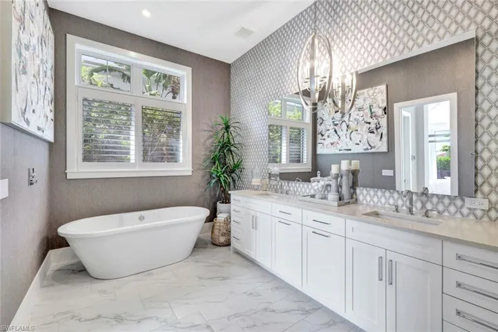 Bathroom with a tub to relax in, vanity, and a chandelier