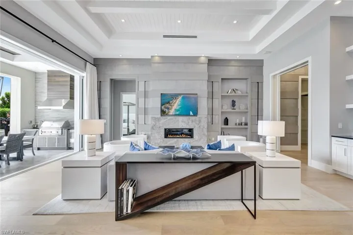 Living room featuring light hardwood / wood-style floors, a raised ceiling, built in features, and a high end fireplace
