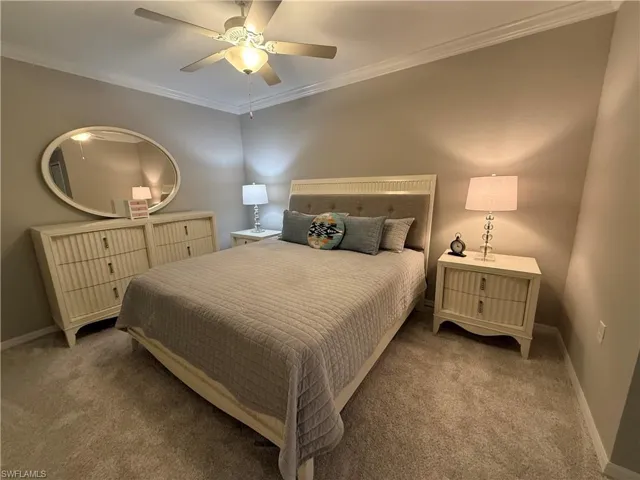 Carpeted bedroom with ornamental molding and ceiling fan