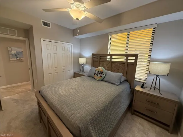 Carpeted bedroom featuring ceiling fan and a closet