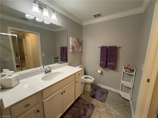 Full bathroom with vanity, crown molding, an enclosed shower, and light tile patterned flooring