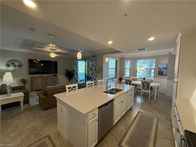 Kitchen featuring white cabinets, light stone countertops, ornamental molding, pendant lighting, and open floor plan