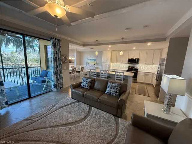Living room with ornamental molding, ceiling fan, and light tile patterned flooring