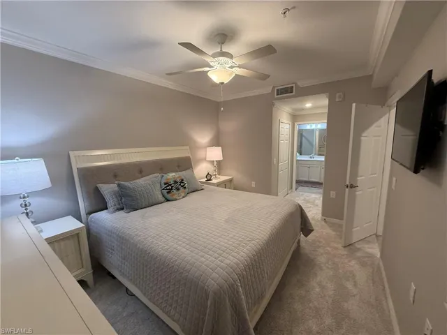 Bedroom featuring ensuite bath, ornamental molding, carpet floors, and ceiling fan