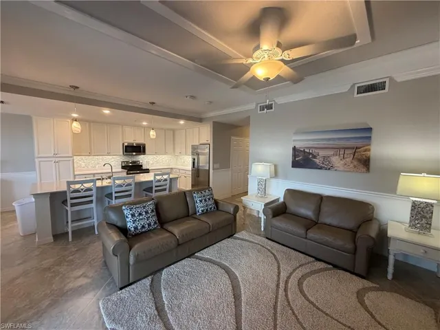 Living room featuring a ceiling fan and crown molding