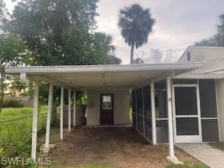 View of parking featuring a carport and bonus enclosed 9'x9' CBS outbuilding