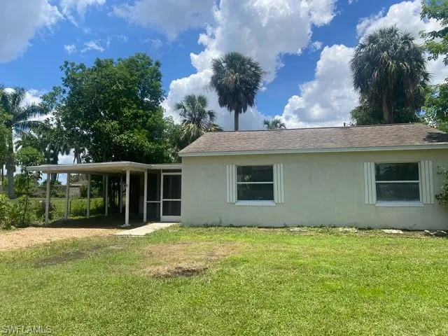 Front of home with a yard, a carport, stucco siding, and a patio