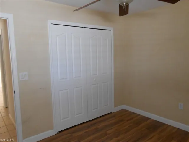 Unfurnished bedroom featuring dark wood finished floors, ceiling fan, and a closet