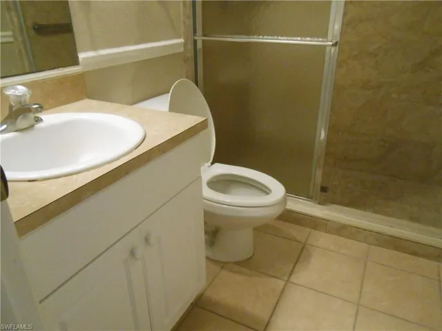 Full bath with a shower stall, vanity, and light tile patterned flooring