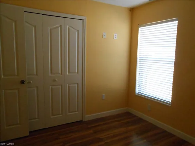 Unfurnished bedroom featuring dark wood-style flooring and a closet