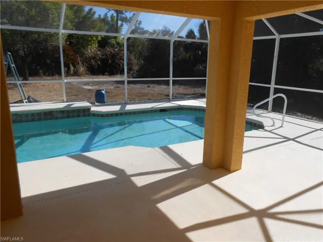 Swimming pool with glass enclosure, a patio area, and a sunroom