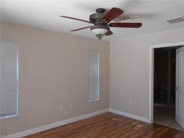 Spare room featuring dark wood-type flooring and ceiling fan