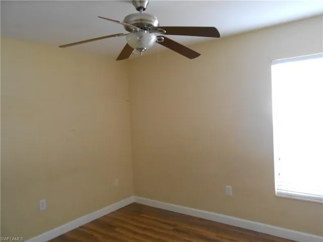 Empty room featuring dark wood-type flooring and a ceiling fan