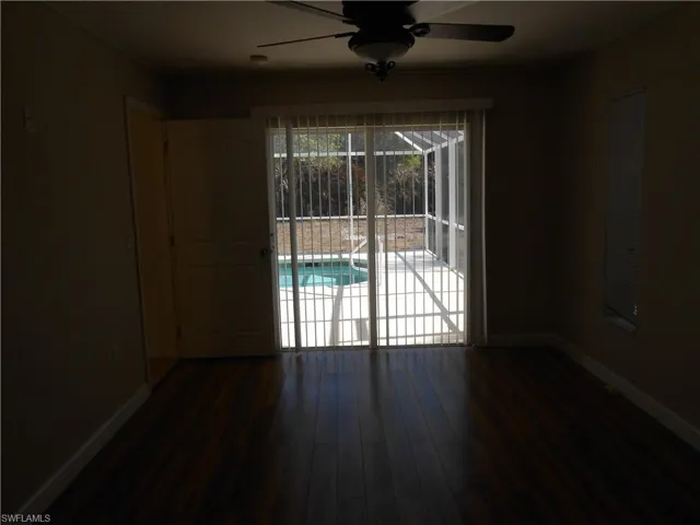 Unfurnished room with a ceiling fan, dark wood-style flooring, and a sunroom