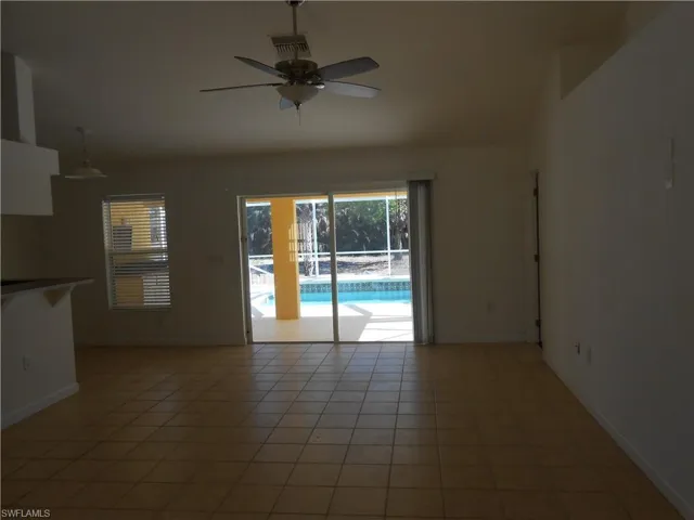 Empty room featuring ceiling fan, light tile patterned flooring, and lofted ceiling