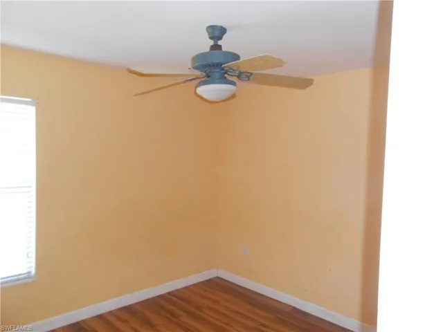 Unfurnished room with dark wood-style floors and a ceiling fan