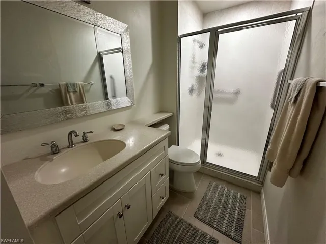 Full bathroom featuring vanity, a stall shower, and dark tile patterned flooring