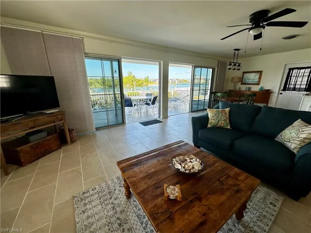 Living area with healthy amount of natural light, ceiling fan, a water view, and light tile patterned floors
