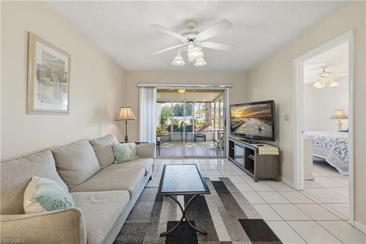 Living area with a ceiling fan, light tile patterned floors, and a textured ceiling