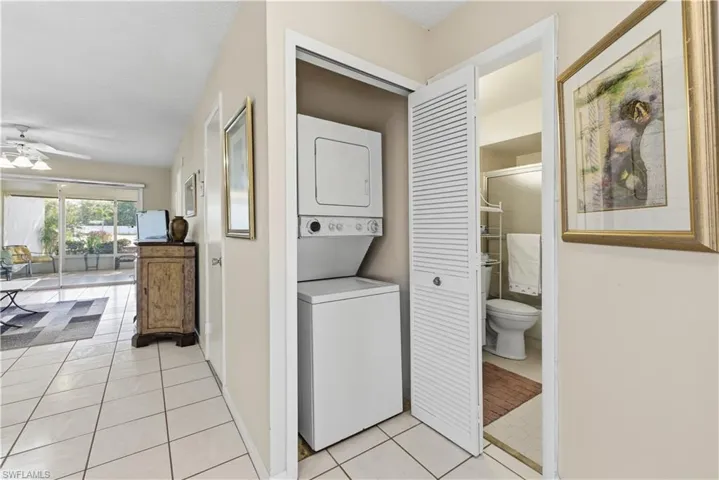 Laundry area featuring estacked washer and dryer, light tile patterned floors, and ceiling fan