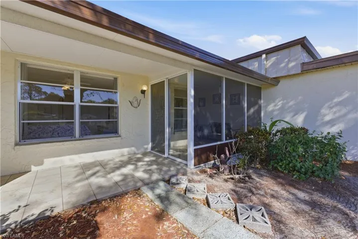 Doorway to property featuring stucco siding, a sunroom, and a patio