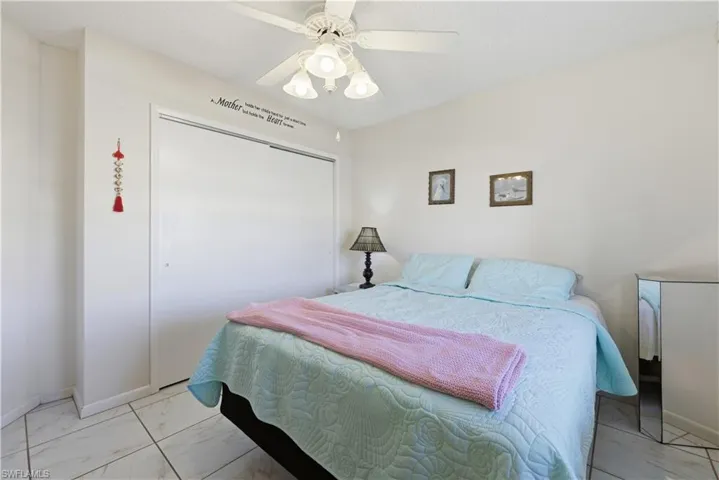 Bedroom featuring a closet, a ceiling fan, and light marble finish flooring