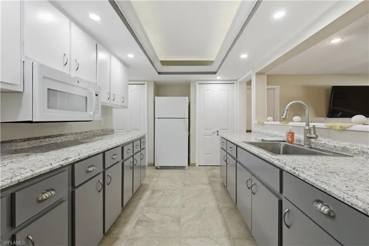 Kitchen featuring gray cabinetry, white appliances, recessed lighting, light stone countertops, and white cabinets